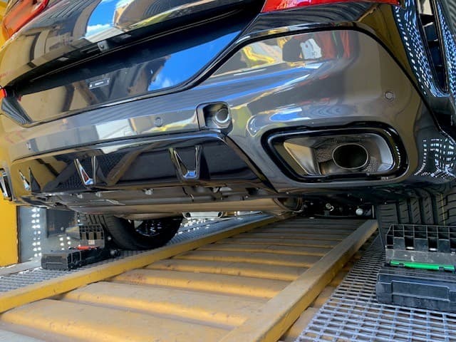 Rear of a customer's BMW positioned over the deck planks inside an enclosed autorack rail car